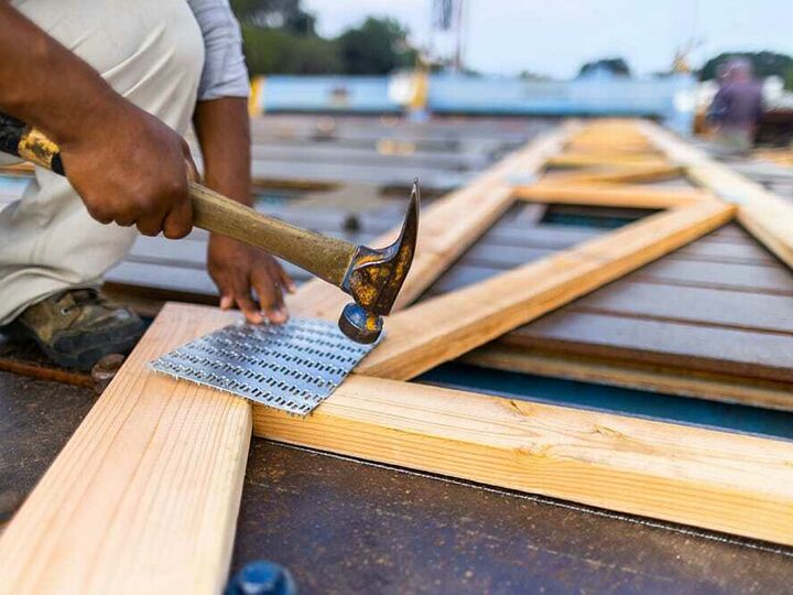 Exchange Bank business loan customer's construction worker nailing framing with hammer.