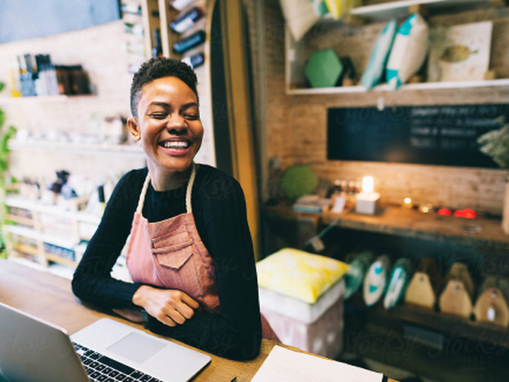 Small-Business-Shop-Owner-Smiling-at-Counter-Near-Point-of-Sale