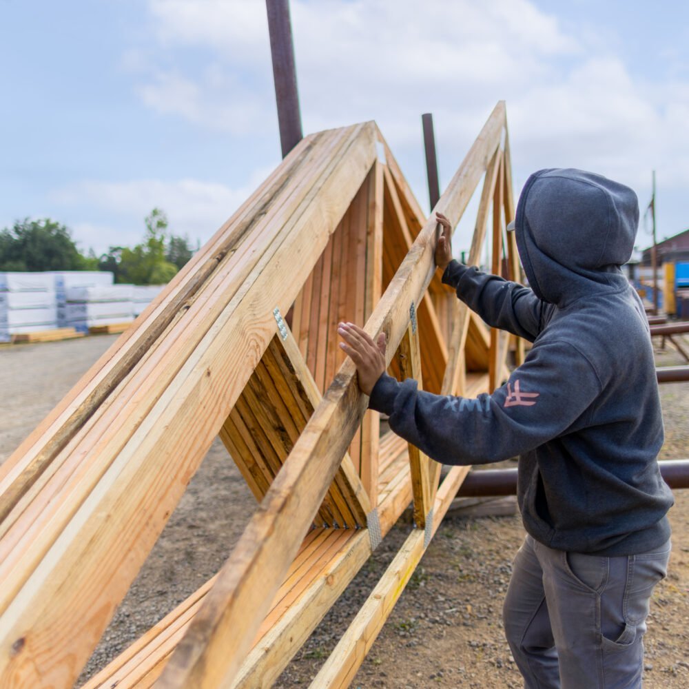 Exchange Bank business customer All Truss worker lifting framing on a job site.