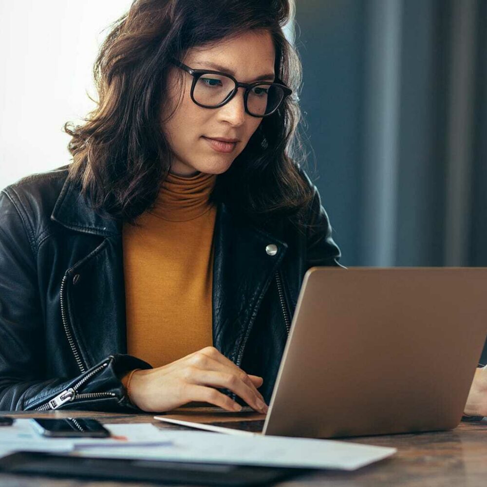 Exchange Bank customer seated at a desk, reviewing information on her laptop.