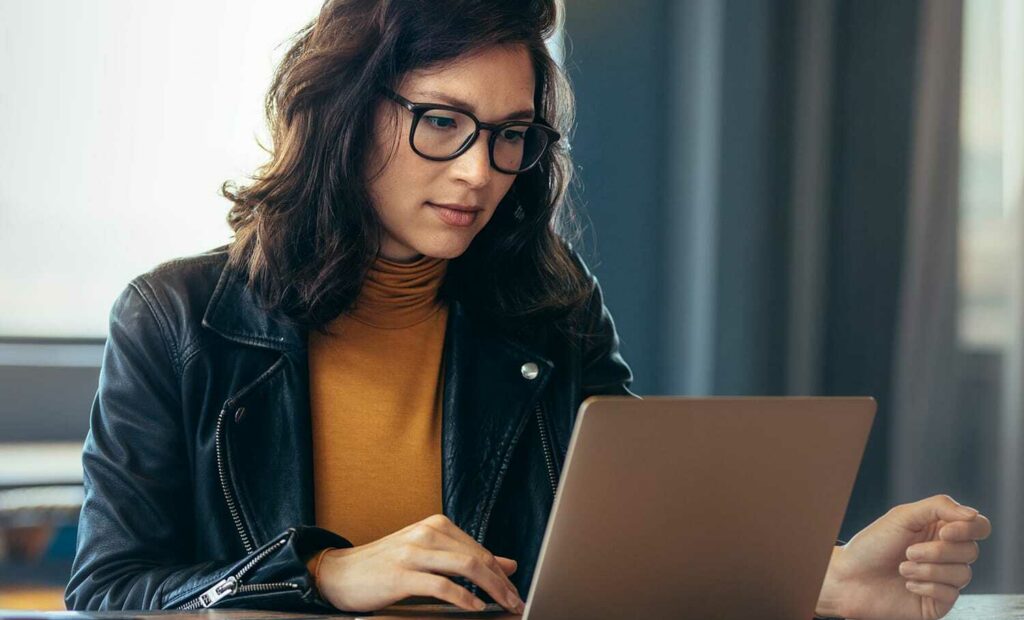 Exchange Bank customer seated at a desk, reviewing information on her laptop.