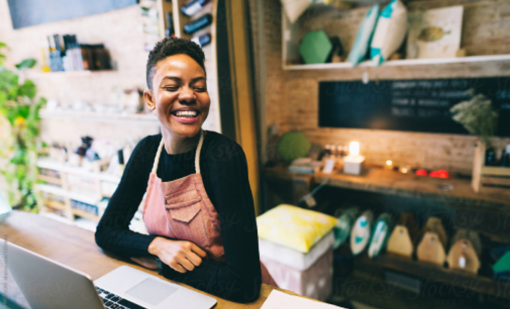 Small-Business-Shop-Owner-Smiling-at-Counter-Near-Point-of-Sale