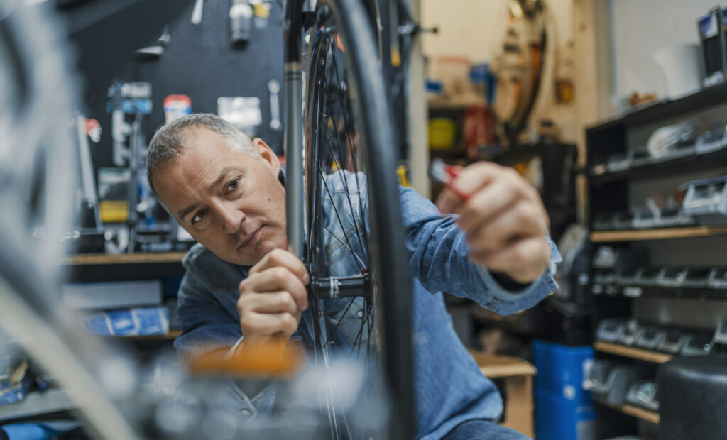 Exchange Bank business customer in a bicycle shop, working on a tire.