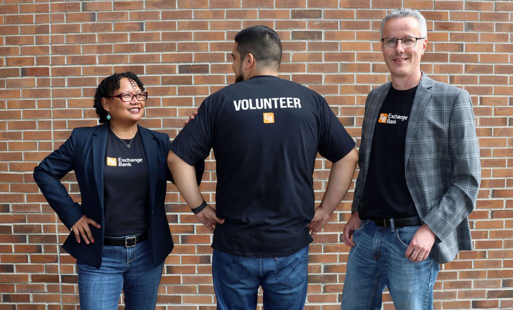 Three bank employees wearing volunteer t-shirts standing in front of Exchange Bank main branch in Santa Rosa, Sonoma County.