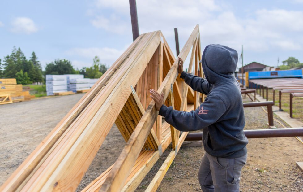 Exchange Bank business customer All Truss worker lifting framing on a job site.